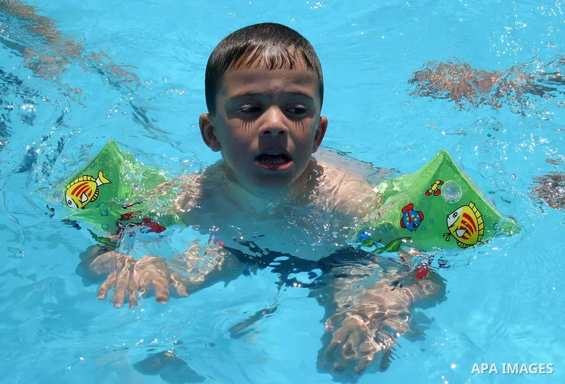 Palestinian boys jump into a swimming pool to cool off during a heat wave, in the West Bank city of Hebron on June 02, 2009. Photo \ Najeh Hashlamoun