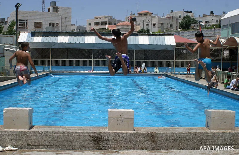 Palestinian boys jump into a swimming pool to cool off during a heat wave, in the West Bank city of Hebron on June 02, 2009. Photo \ Najeh Hashlamoun