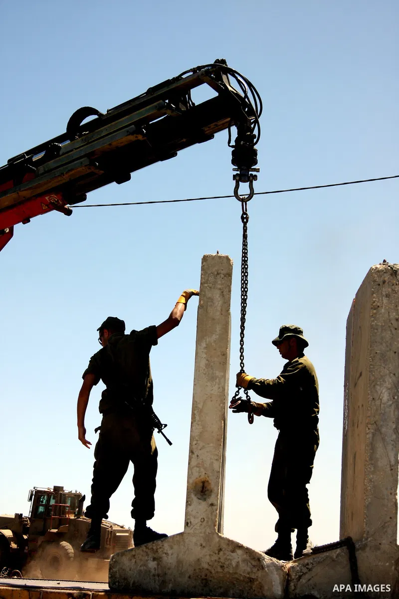 An Israeli crane operator lifts a concrete block with a crane as the Israeli army starts removing the so-called Bir Zeit checkpoint near the West Bank city of Ramallah June 3, 2009.US President Barack Obama embarks on hi...