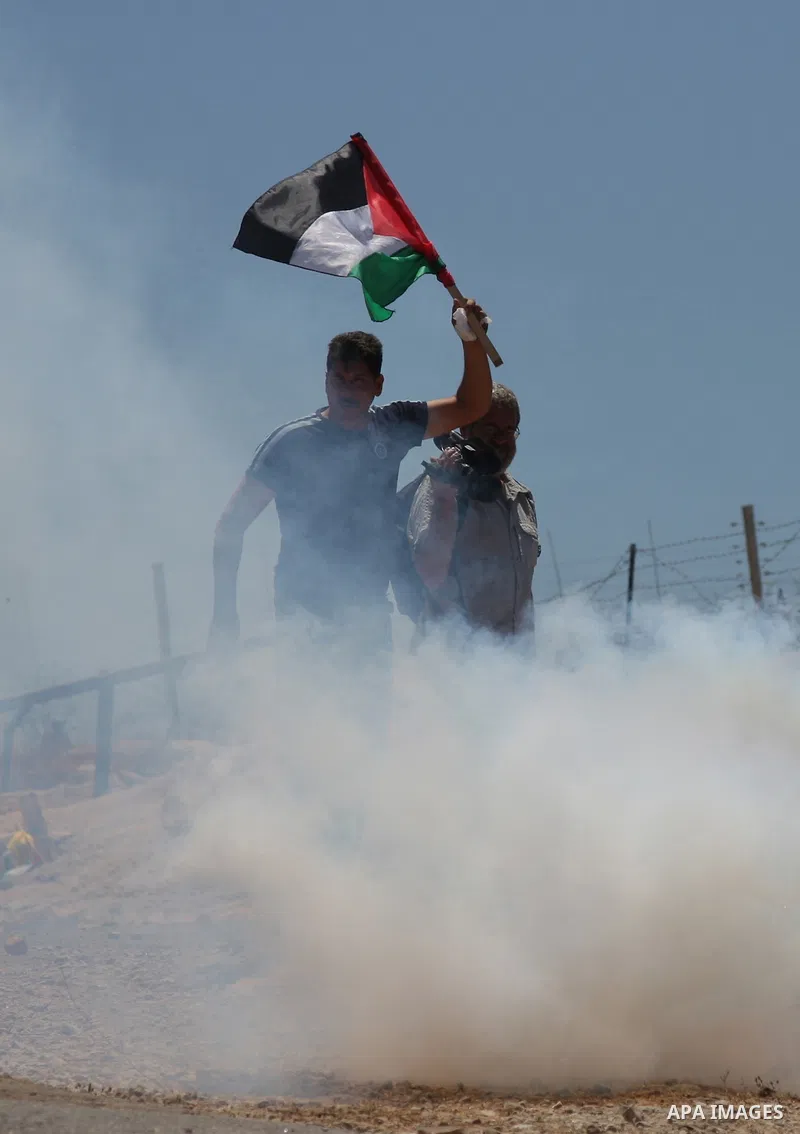 A Palestinian youth runs for cover as Israeli soldiers fire teargas during a protest against the Israeli controversial separation barrier in the West Bank village of Bilin near Ramallah. on June 5, 2009.APAIMAGES PHOTO /...