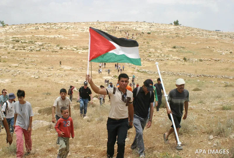 A Palestinian holds Palestinian flag during a demonstration against settlements near Sousia in the southern West Bank, south of Hebron on Saturday June 06, 2009. Photo Najeh Hashlamoun.