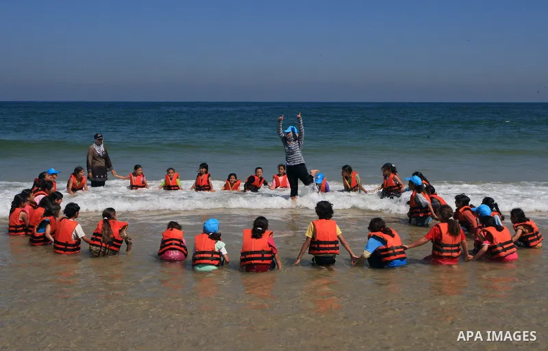 Palestinian children and their instructors walk into the water wearing life vests as they attend a UN Relief and Works Agency, (UNRWA), Summer Games camp on the beach of Gaza City on June 29, 2009. photo by Wissam Nassar
