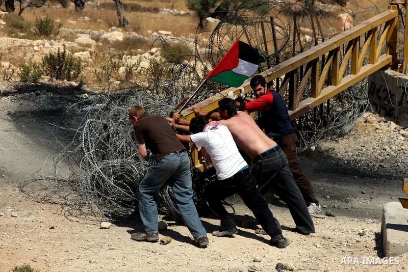 A Palestinian and foreign protesters clash with Israeli soldiers during a demonstration against Israel's controversial separation barrier in the West Bank village of Bilin near Ramallah on July3,2009. Photo by Issam Rima...