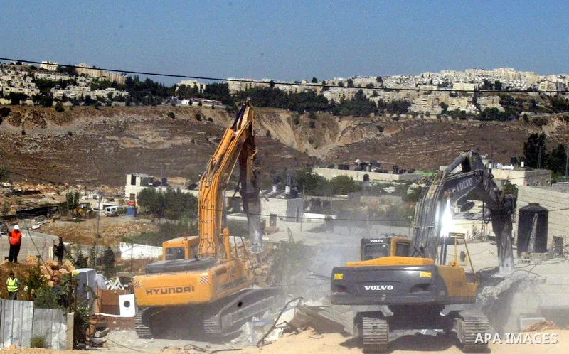 Israeli bulldozers demolish a Palestinian house that was built without a construction permit, in the Arab Jerusalem neighborhood of Beit Hanina, on July 13, 2009. In the background, the Israeli settlement of Ramat Shlomo...
