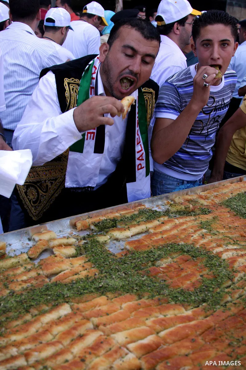 Palestinians eat of the biggest dish of traditional sweets "Konafa" into the Guinness Book of Records in the West Bank city of Nablus on July 18 2009. Photo by Issam Rimawi