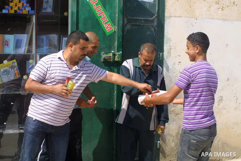 A Palestinian student distributes sweets after his success of general secondary certificate in the West Bank city of Ramallah on July 21, 2009. Photo By Nedal Shtieh