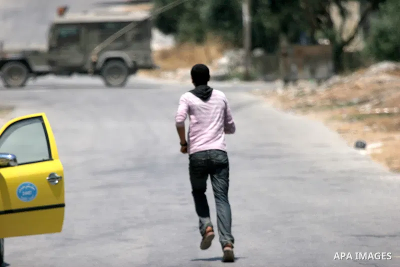 A Palestinian youth runs to throw stones at Israeli jeeps during raid for Israeli troops in the west bank of Nablus on July 22 ,2009. Photo by Nedal Shtieh