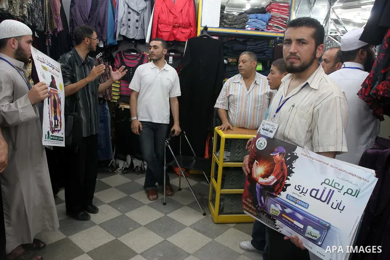 Palestinian youths distributing posters calling for the commitment of the Islamic Shariah, the Islamic dress, the veil and the rejection of nudity and porn sites and drugs during El-Fadila campaign organized by of the Mi...