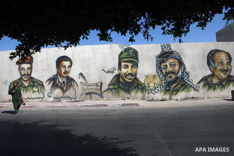 A Hamas policeman stands guard on a street with images of late Fatah leaders, including Yasser Arafat, are seen in the background in Gaza city on Aug 5, 2009. Hamas has prevented the Gaza-based Fatah members from traveli...