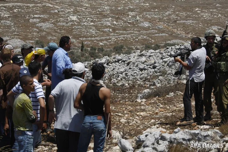 Israeli settlers point thier weapons at Palestinian demonstrators during a protest near the Jewish settlement of Bracha, south of the West Bank city of Nablus on August 7, 2009. Photo by Nedal Shtieh