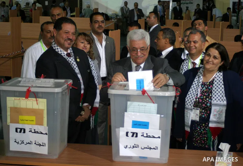President Mahmoud Abbas walks past desks that serve as ballot booths, accompanied by an election monitor, as he goes to the ballot boxes after completing his ballot for elections to both the Central Committee and the Rev...