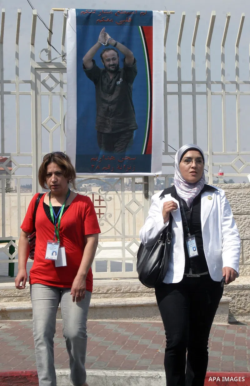 An election committee employees are walking near a banner depicting Marwan Barghouthi outside the Fatah congress in the West Bank town of Bethlehem on August 11, 2009. Photo by Najeh Hashlamoun