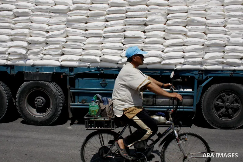 A Palestinian man rides his bycicle in front of UN truck loaded by flour sacks at a UN Relief and Works Agency (UNRWA) warehouse in the Shati refugee camp, in Gaza City, on August 18, 2009. UNRWA launched Monday its Gaza...