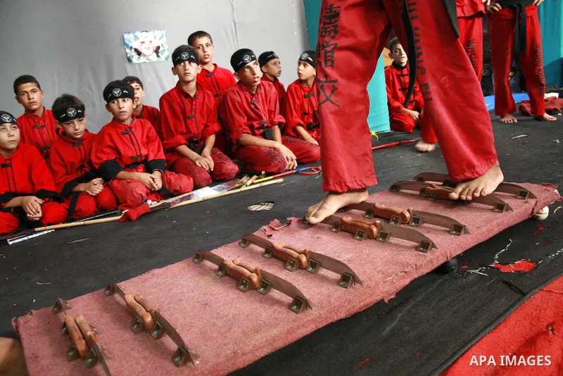 A Palestinian boy stands on knives during a training session at the Red Dragon martial arts club in Beit Lahia, northern Gaza Strip, on August 19, 2009. Since the Israeli offensive on the Gaza Strip earlier this year, an...