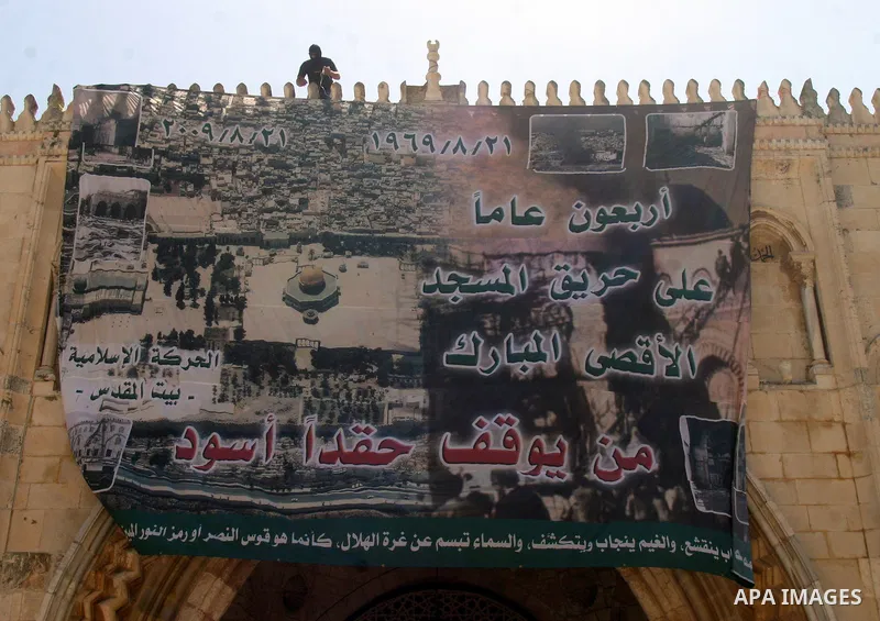 A Palestinian masked supporter of islamic movement hangs a placards calling muslims to liberate Alaqsa mosque in the memorial marking of burning Alaqsa mosque in 1969 and one day before starting of ramadan the fasting ho...