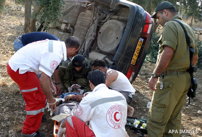 An Israeli soldiers and Palestinian paramedics relief to injured Palestinians, after a traffic accident near the West Bank city of Hebron , 21 August 2009. Photo by Najeh Hashlamoun