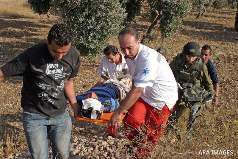 An Israeli soldiers and Palestinian paramedics relief to injured Palestinians, after a traffic accident near the West Bank city of Hebron , 21 August 2009. Photo by Najeh Hashlamoun