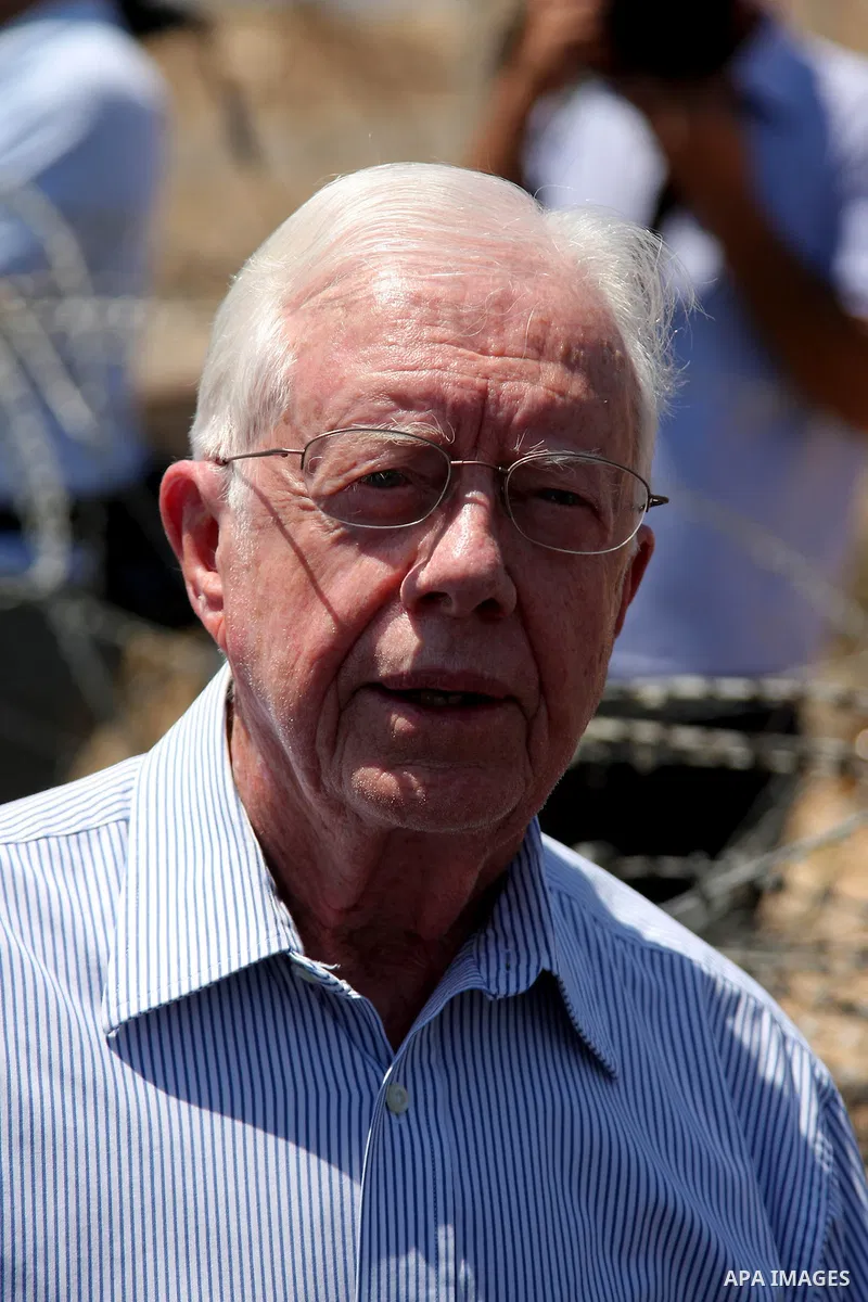Former U.S. President Jimmy Carter stands in front of the controversial Israeli barrier during a visit to the West Bank village of Bilin near Ramallah August 27, 2009. The delegation from the group known as "The Elders"...