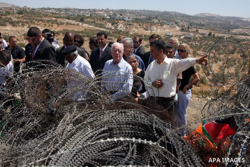 The Elders, a group of eminent global leaders And Former U.S. President Jimmy Carter stands in front of the controversial Israeli barrier during a visit to the West Bank village of Bilin near Ramallah August 27, 2009. Th...