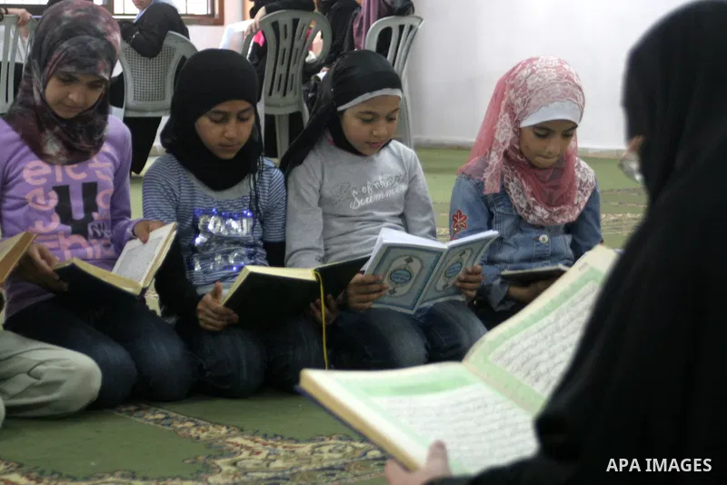 A Palestinian Muslim girls, reads verses of the Quran, Islam's holy book, while waiting to break her daily fast during the Muslim holy fasting month of Ramadan, in a mosque in the West Bank city of Nablus, Saturday, Aug....