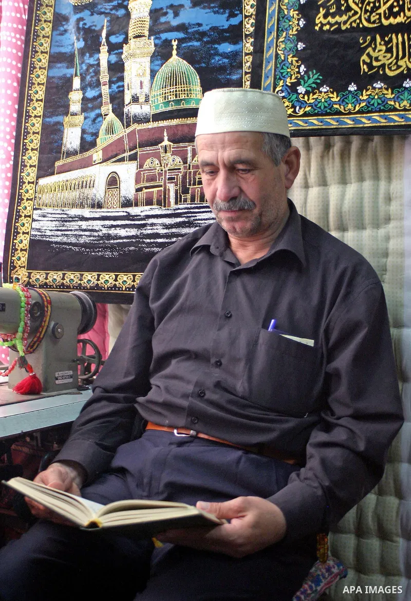 A Palestinian man reads the Koran, Islam's holy book, as he sits in front of his shop in the old city of Hebron, in the West Bank, on September 07, 2009. During Ramadan, Muslims have to abstain from eating and drinking f...
