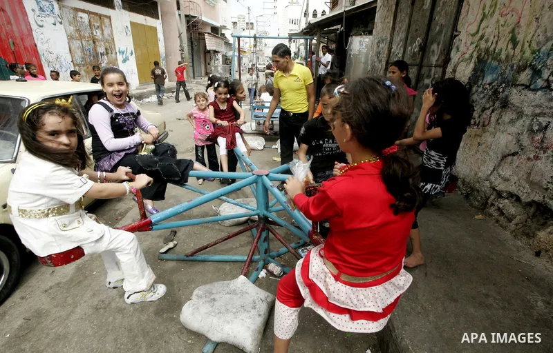 Palestinians enjoy a ride at an amusement park during the second day of the holiday of Eid al-Fitr in Rafah refugee camp in the center of southern Gaza on the first day of the Muslim holiday Eid al-Fitr, on September 21,...
