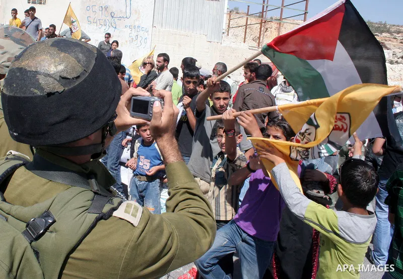 Israeli soldiers stand guard behind razor-wire during a rally by Palestinian and foreign protestors against Israel's separation barrier in the West Bank village of Maasarah, near Bethlehem, on September 25, 2009.Photo by...
