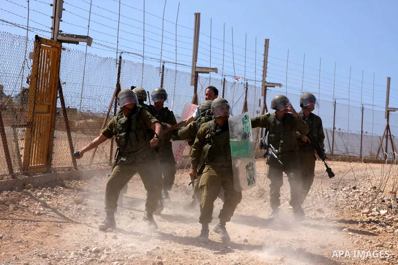 An Israeli soldier throws a tear gas grenade at demonstrators during a protest against the controversial Israeli barrier in the West Bank village of Bilin near Ramallah on Sep 25, 2009. Photo by Issam Rimawi
