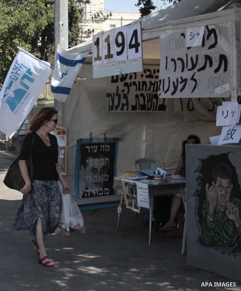 A Pedestrian walks past a banner, depicting captured Israeli soldier Gilad Shalit, hung outside a protest tent calling for his release, near the residence of Israel's Prime Minister Benjamin Netanyahu in Jerusalem Septem...