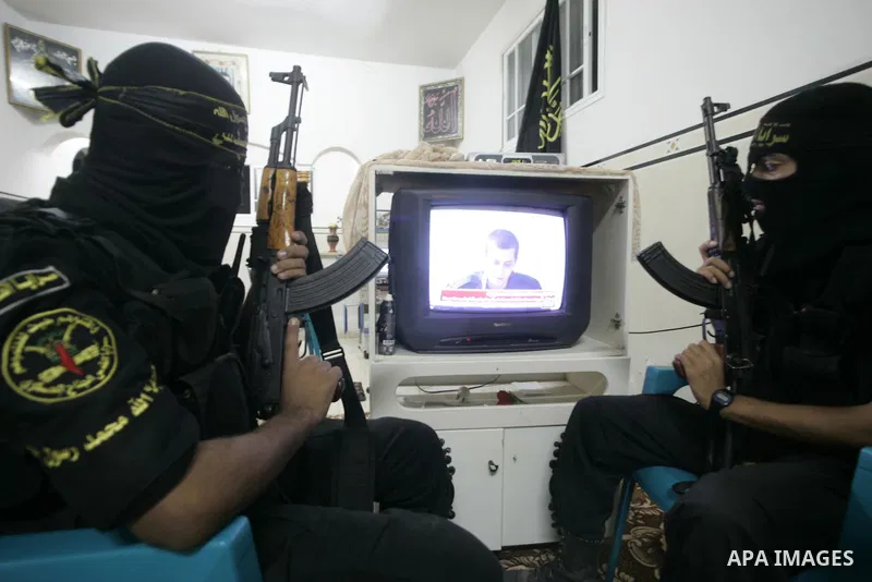 Palestinian Islamic Jihad militants wear masks to conceal their identities as they watch the video tape of a captive, Corporal Gilad Shalit on television during the news bulletin in Rafah, southern Gaza Strip on October...