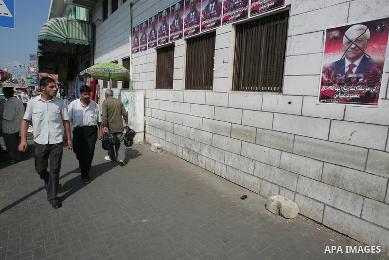 Palestinian men walk past posters of Palestinian president Mahmud Abbas with a phrase reading in Arabic, "to the dust bin of history, traitor" are plastered in a street in Gaza City on October 7, 2009. Hamas warned that...