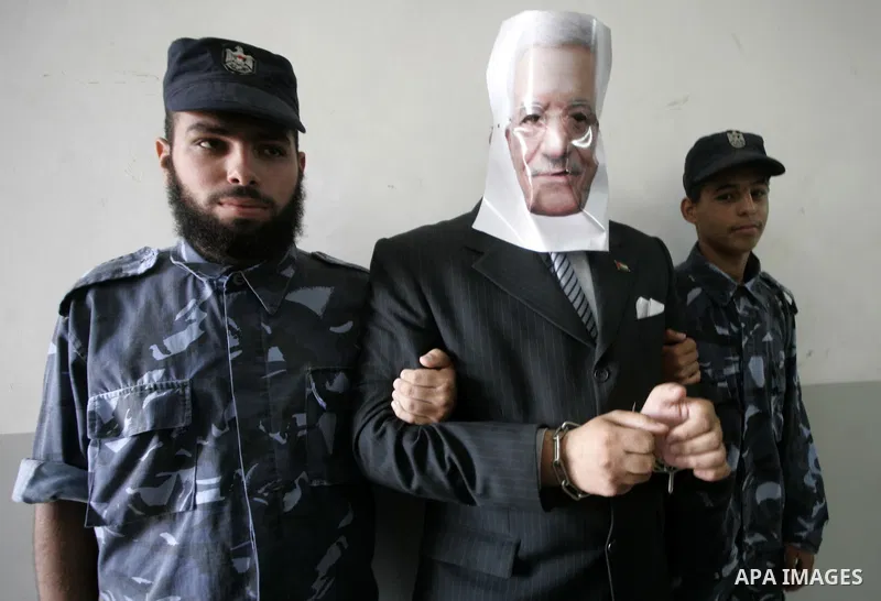 Hamas supporters, playing the role of policemen hold a palestinian boy wearing a mask of Palestinian president Mahmud Abbas , stands behind bars during a mock trial in the Rafah refugee camp, southern Gaza Strip, on Octo...