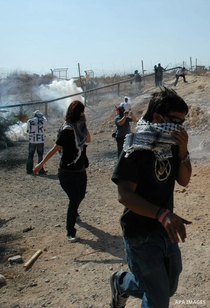 Protestors run to cover from the gas tears grenades during a demonstration against Israel's separation barrier in the West Bank village Billin near Ramallah on Oct 23, 2009. Photo by Nedal Shtieh