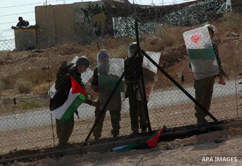 Israeli soldiers remove a palestinian flag placed by demonstrators during a demonstration against Israel's separation barrier in the West Bank village Billin near Ramallah on Oct 23, 2009. Photo by Nedal Shtieh