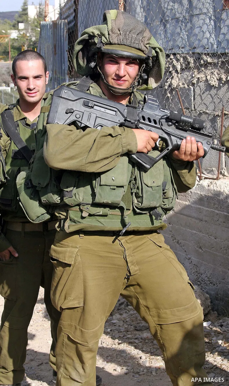 Israeli soldiers stand guard as Palestinians, Israelis and foreign activists attend a protest against Jewish settlement within the West Bank near Kiryat Arba settlement in the West Bank city of Hebron October 23, 2009. P...
