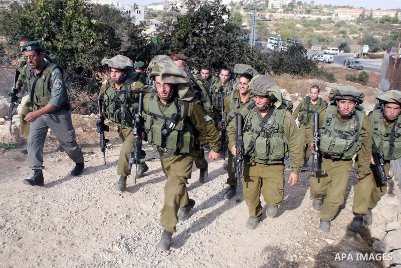 Israeli soldiers stand guard as Palestinians, Israelis and foreign activists attend a protest against Jewish settlement within the West Bank near Kiryat Arba settlement in the West Bank city of Hebron October 23, 2009. P...