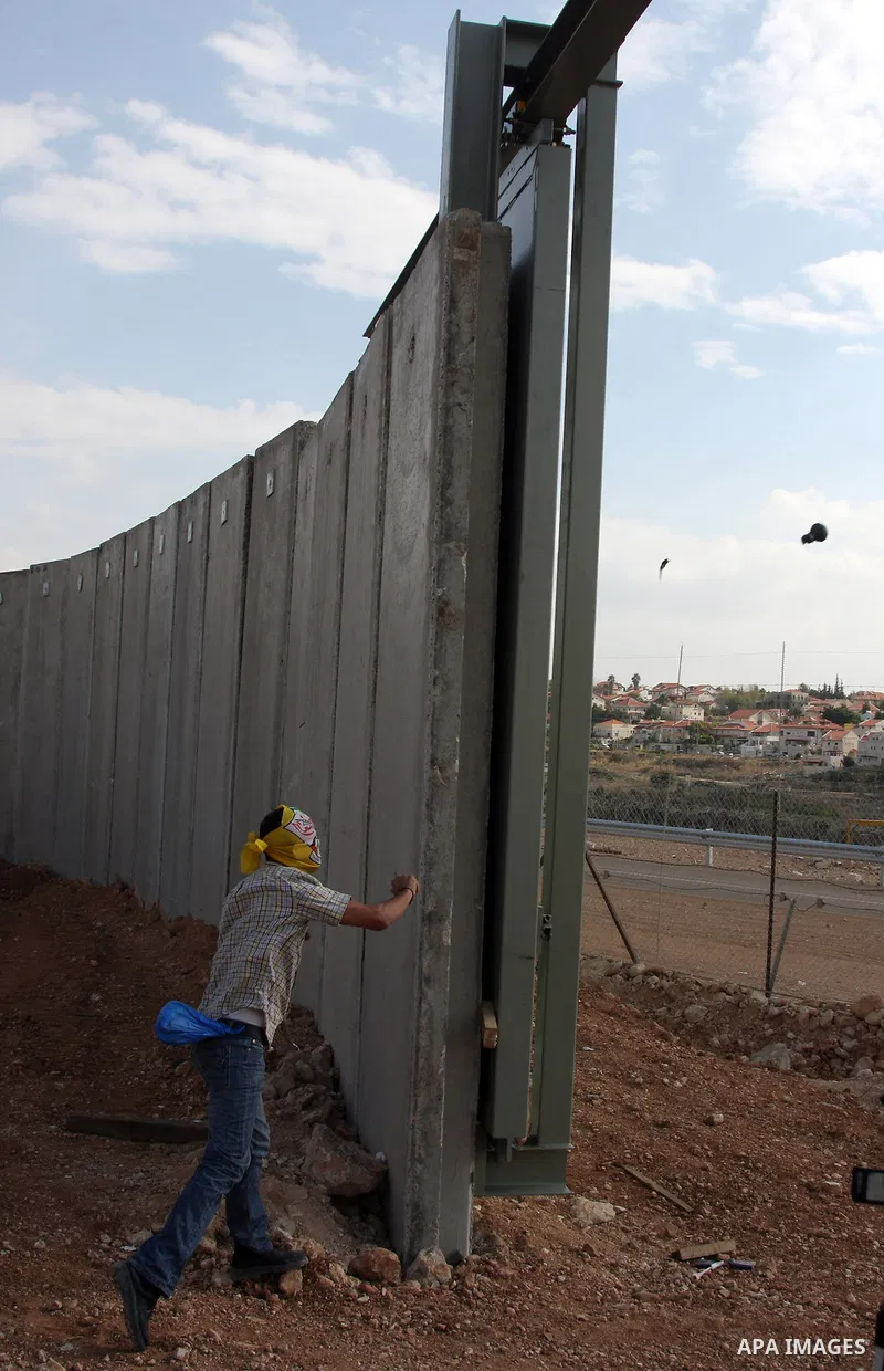 Palestinian youth throws stones during a demonstration against Israel's controversial separation barrier in the West Bank village of Nilin, near Ramallah, on Dec 4, 2009. Israel says the projected 723 kilometres (454 mil...