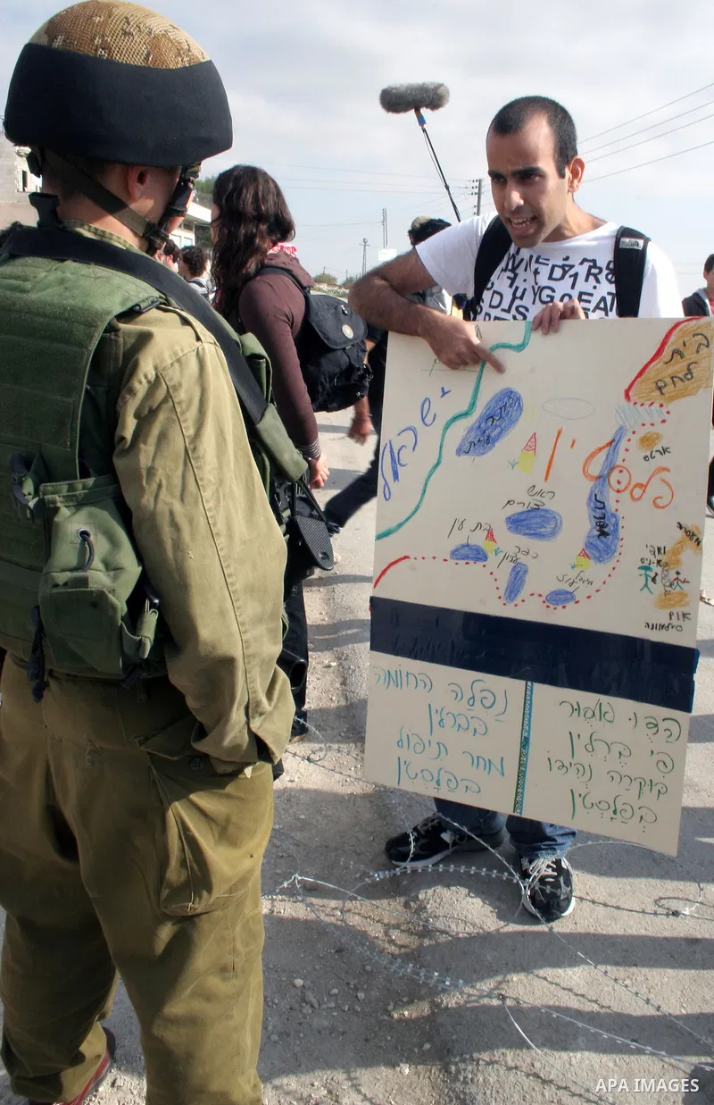 Israeli soldiers and Israeli border policemen stand guard behind razor-wire as Palestinian , Israeli activists and International activists during a rally against Israel's separation barrier in the West Bank village of al...