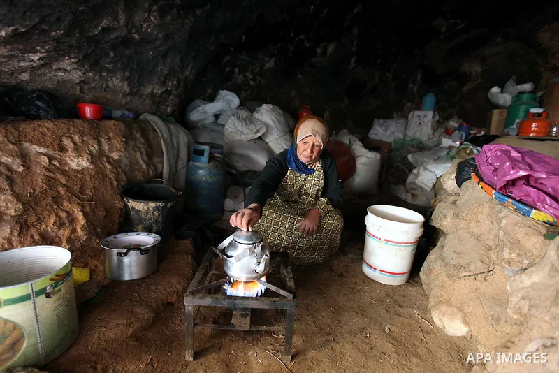 Palestinian woman makes tea as she sits inside a cave in a mountainous area outside the southern town of Yatta near Hebron in the occupied West Bank on December 5, 2009. Palestinian residents of the area have returned to...