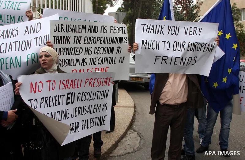 Palestinian demonstrators hold banners during a rally in front of the compound housing the French and Swedish consulates in east Jerusalem on December 7, 2009 in support of a draft EU proposal that east Jerusalem should...
