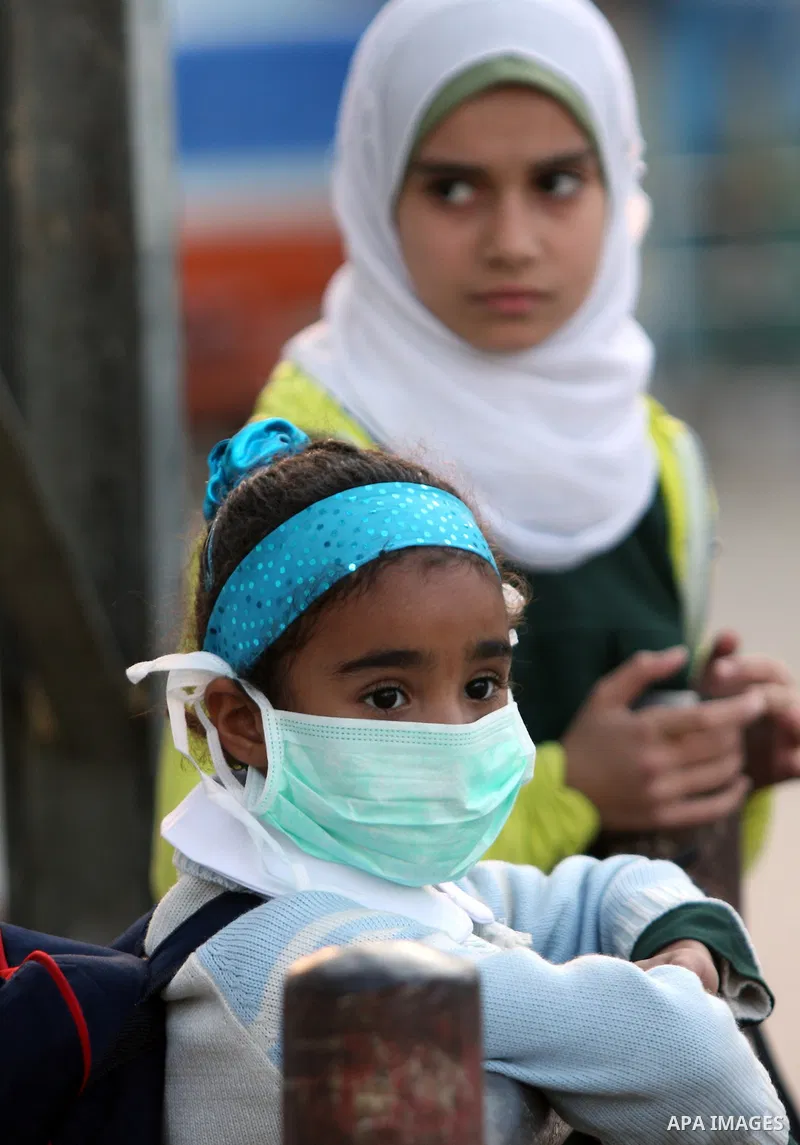 Palestinians wear face masks on a street in Gaza city for fears of A/H1N1 virus in Gaza city on Dec 13, 2009. The virus killed a sixth Palestinian victim since it was discovered in the Gaza Strip on Sunday. photo by Wiss...