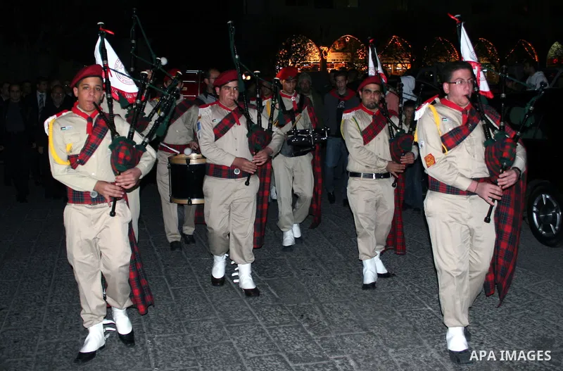 Palestinian scouts perform near a lit Christmas tree at Manger Square, outside the Church of the Nativity in the West Bank city of Bethlehem on December 15, 2009. Christians Pilgrims and tourists are expected to visit Be...