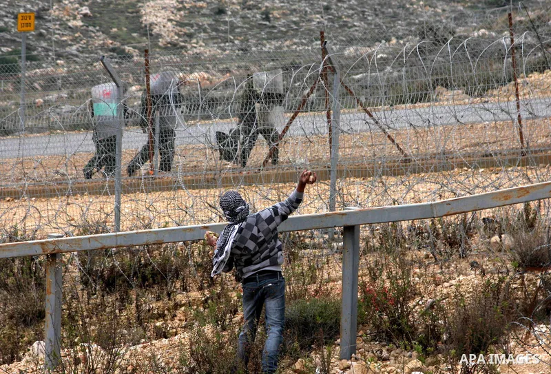 Palestinian youth throws stones during a demonstration against Israel's controversial separation barrier in the West Bank village of Billin, near Ramallah, on Dec 18, 2009. Israel says the projected 723 kilometres (454 m...