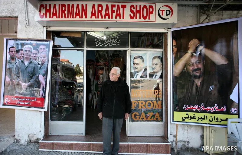 A Palestinian man walks past a shop in Gaza City, displaying posters of Fatah leader Marwan Barghuti (R) and Popular Front for the Liberation of Palestine (PFLP) leader Ahmed Saadat (L), both jailed in Israel, on Decembe...