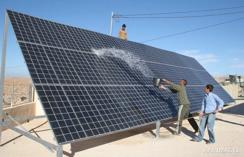 Palestinian men cleaning a solar panel with water, in the West Bank village of Mneizel southern the West Bank city of Hebron, 27 December 2009. ..