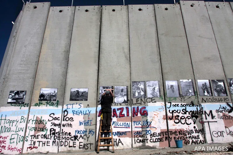 An Italian tourist depicting paint pictures on the Israeli controversial separation barrier in the West Bank city of Bethlehem on December 28, 2009. Photo by Mohamar Awad