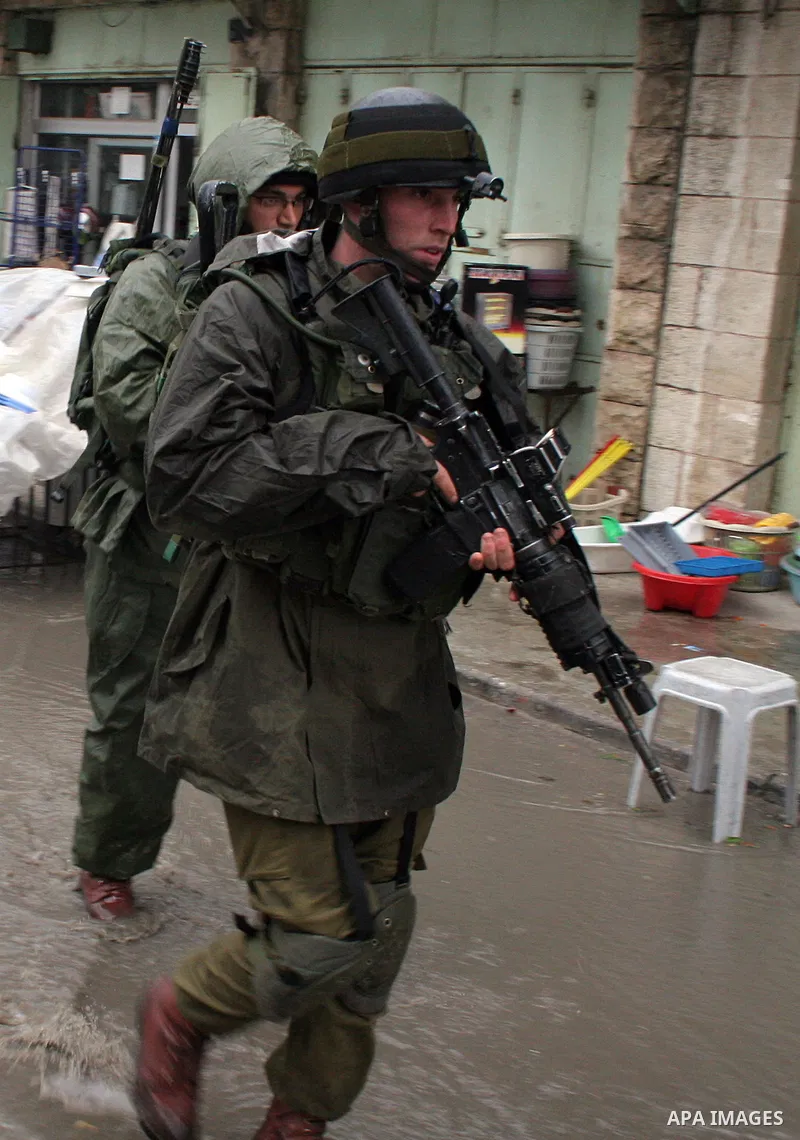 Israeli soldiers patrol a market during the heavy rains in the West Bank city of Hebron on 30 December 2009. Photo by Najeh Hashlamoun