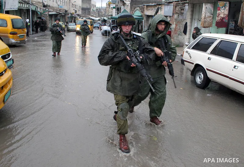 Israeli soldiers patrol a market during the heavy rains in the West Bank city of Hebron on 30 December 2009. Photo by Najeh Hashlamoun