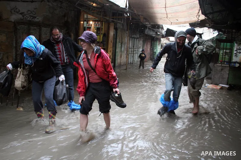 Palestinians and foreigners walking in the market during heavy rains in the West Bank city of Hebron on 30 December 2009. Photo by Najeh Hashlamoun