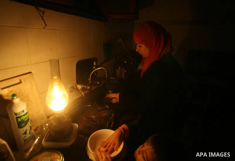 A Palestinian woman uses a kerosine lamp as she works in her kitchen during a power cut in Gaza city's Shati refugee camp on January 24, 2010. Gamal Dardasawi director of public relations in the electricity distribution...